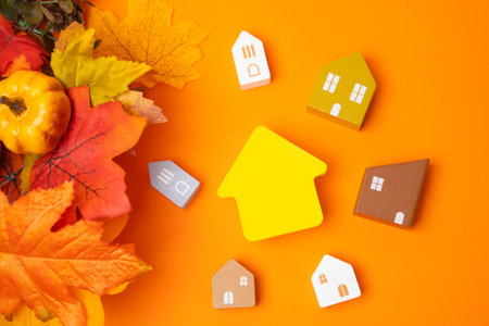 Miniature houses and autumn leaves on orange background. Autumn and real estate concept. Decor and decorations. Flat layの写真素材