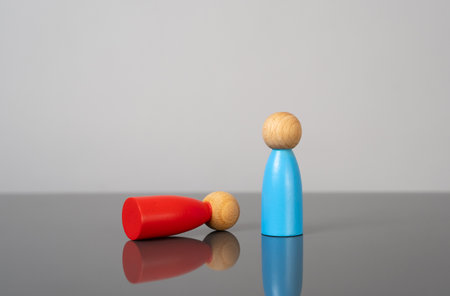 The blue figurine is standing upright while the red figurine is lying down. The concept of competition, dispute or rivalry. Sports victories, or political debatesの写真素材