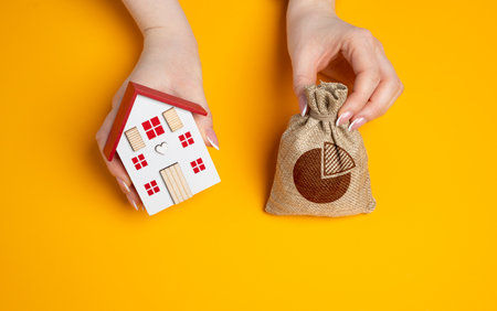 House and a bag with a budget in hands. Family budget concept. Managing housing expenses, bills and building maintenance. Housing expenses. Property investment. Balancing household finances.の写真素材