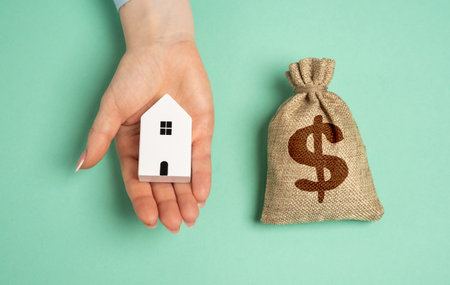 Hand offers house in exchange for money in bag. Buying a house. Possible housing options on a budget. Real estate transactions. Mortgage planning, homeownershipの写真素材