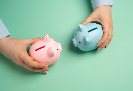 Two piggy banks in hands. Concept of financial relations in a couple or family. Common or separate budget for spouses. Financial dynamics in relationships. Household budgets.の写真素材