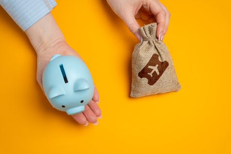 Piggy bank and a bag of airline tickets. The concept of saving on flights, accumulating bonuses and air miles. Discounts and promotions, great deals. Low-cost airlines. Reducing travel costs.の写真素材