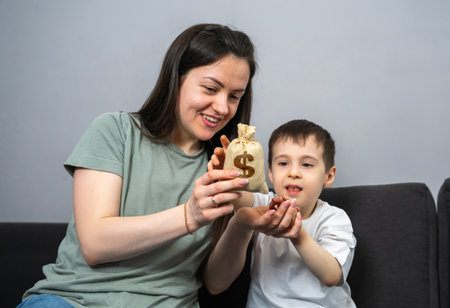 Mom gives her son a dollar money bag. Financial literacy, learning the value of money. Heritage. Family budget. Money for future college. Developing budgeting skills, understanding wealth managementの写真素材