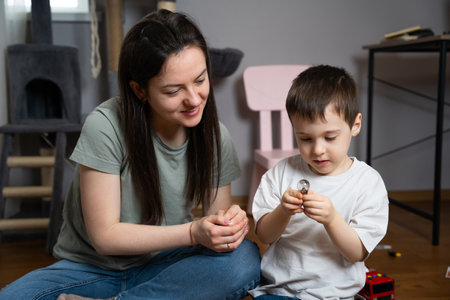 Little boy studying a light bulb with his mother. Educational games, learning about the world. Sparking curiosity about science, energy, and inventions. Understanding of technology and innovation.の写真素材