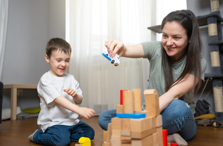 The boy plays with wooden blocks with his mother. Strengthening family bonds while developing fine motor skills, logic, and imaginative thinking. Teamwork, creativity, and educational play.の写真素材