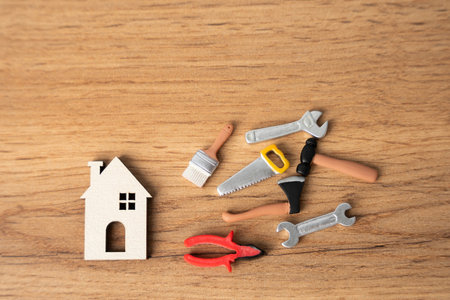 Miniature house and repair tools: pliers, saw, brushes, hammer. Concept of repair and maintenance of housing.の写真素材