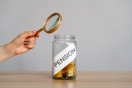 Bank of coins and the inscription Pension. Saving money and retirement concept. Accumulation of pension contributions. Business and finance. Magnifying glassの写真素材