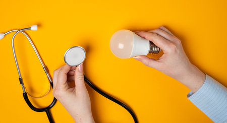 Lamp bulb and stethoscope in female hands. Innovations and ideas in medicine, new concepts, treatments, technologies, and approaches that aim to improve healthcare, solve medical challengesの写真素材