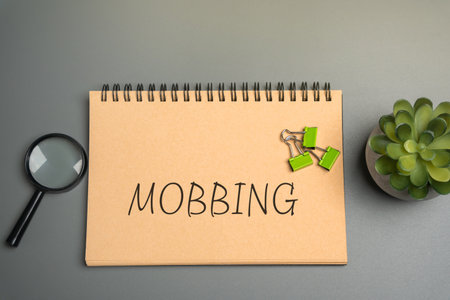 Mobbing concept. Act of bullying or harassing a person, typically in a workplace or school setting, where a group of people targets an individual with persistent mistreatment. Notepad with inscriptionの写真素材