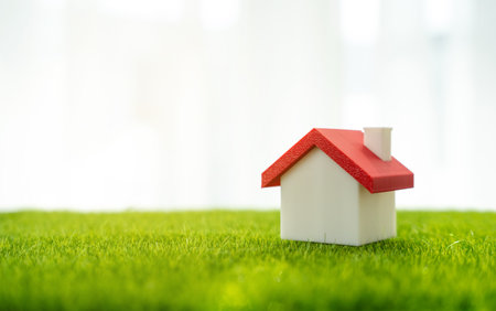 Figurine of a house on the grass. Real estate and housing. Suburban housing, property value, or land purchase, housing markets or green real estate. Eco-living.の写真素材