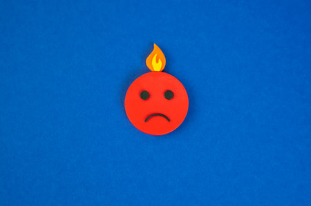 An evil face and fire on the head. A metaphor for a nervous breakdown and burnout. High stress, mental overload, and psychological exhaustion.の写真素材