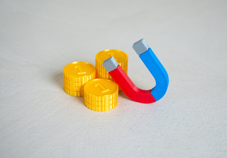 Stack of money coins and magnet. Concept of attraction of financial resources. Learn to earn money. Business development, financial coaching, or passive income strategies. Attracting moneyの写真素材