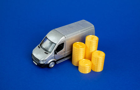 A delivery van with a stack of cash coins. Delivery of goods, economics of the logistics industry. Cost of transportation services, e-commerce revenue, supply chain. Retail and trade.の写真素材