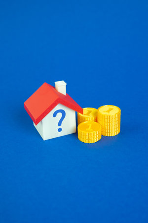 House with a question mark and coins. Property and real estate valuation. Real estate market forecasts. Pricing, appraisals, buyer hesitation, or investment risks. Mortgage evaluationの写真素材