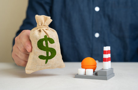 Man holding dollar money bag near industrial chemical plant. Investments in energy and biochemical industry sector. Investment in biofuels. State-backed industrial expansion. Energy transitionの写真素材