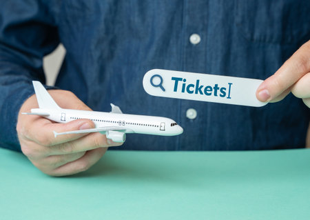 Man holds plane and search bar for tickets. Travel planning. Ticket booking. Online search. Vacation preparation. Passenger convenience. Flight scheduleの写真素材