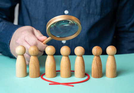 A man evaluates people figures through a magnifying glass. Search for candidates. Selection of people. HR management. Candidate review. Employment choice. Workforce selection.の写真素材