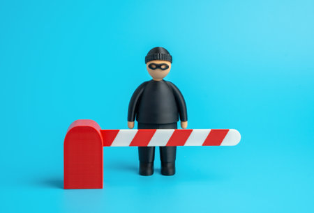 A masked thief behind a barrier gate. Stop crime. Cyber protection from hackers and industrial espionage. Security, data defense, and system integrity. IT, finance, and risk management themes.の写真素材
