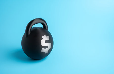 A weight with a dollar symbol. Debt burden. Financial pressure and economic instability. Credit obligations, bankruptcy risk, and loan repayment challenges in business and personal financeの写真素材