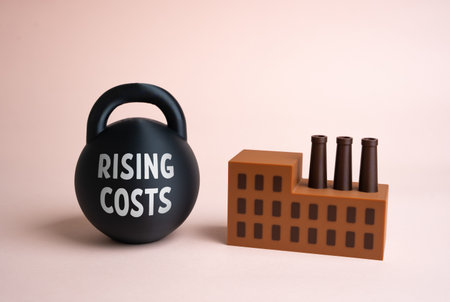 An industrial factory and a weight with rising costs. Changing economic conditions, rising prices for resources and energy, increasing taxes and wages. Business adaptation.の写真素材