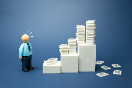 An office worker is amazed at the accumulated paper work. Bureaucracy and ineffective organization of work and reporting. Office overload and administrative inefficiency. Workplace stressの写真素材