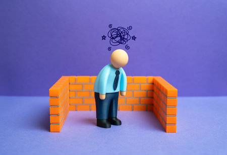 A depressed office worker surrounded by walls. Open your mind, see new possibilities. Break free from routine and comfort zone. Concept of burnout, isolation, and psychological barriers in work life.の写真素材