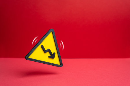 Warning sign with a downward arrow. Declining revenue. Losses and reductions. Budget cuts and reductions. Layoffs. Economic downturn analysis, crisis management and corporate financial reporting.の写真素材