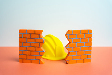 A construction worker's hard hat in a wall crack. Architectural repair and demolition service. Building safety issues, infrastructure maintenance and urban renovation challenges.の写真素材
