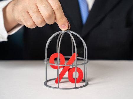 The businessman keeps interest rates in a cage. Stop the growth of loan interest rates. Credit holidays. Financial policy discussions, banking regulation reports and economic stabilityの写真素材