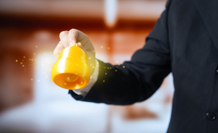 A bell in a businessman's hand. Attract attention, business notifications. Alerts, signals and calls to action in corporate communication. Marketing, management tools and information flow.の写真素材