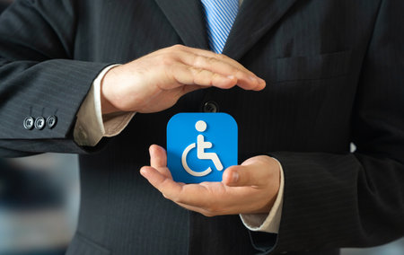 A businessman holds a symbol for people with disabilities. Support for people with limited mobility....