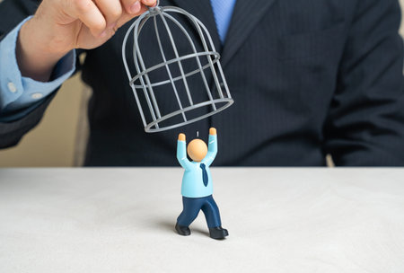 A businessman is trying to trap an employee in a cage. Stop them from quitting or fire them. Workplace coercion and violation of workers rights concept.の写真素材