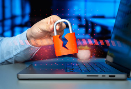 A cracked padlock in a man's hand over a laptop. Hacked security system and corporate data leakage...