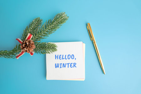 Notes Hello winter and a Christmas tree branch and pen. Concept of the beginning of a new winter season and new month
