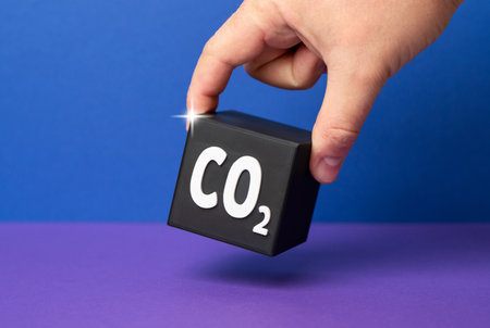 A hand places a CO2 cube. Personal carbon footprint. Individual carbon emissions. Environmental impact. Climate change awareness, air pollution concerns. Environmental responsibility