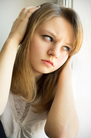 sad girl looking out the window, in the houseの写真素材