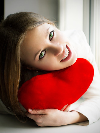 happy girl keeps the heart, lies on the windowの写真素材