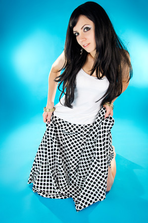 adult girl dancing in Oriental style squat down on a blue backgroundの写真素材
