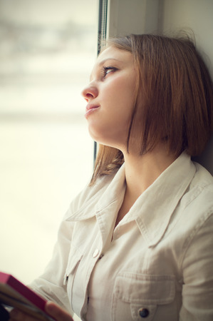 Beautiful girl is sad, sadness due the guy keep picture sit near the windowの写真素材