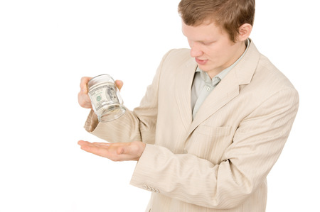 a young guy trying to extract money from a glass container isolated on white backgroundの写真素材
