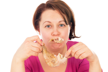 Full woman greedily absorbing piece of chicken, isolated on white backgroundの写真素材