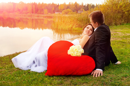 newlyweds sitting on the grass on natureの写真素材