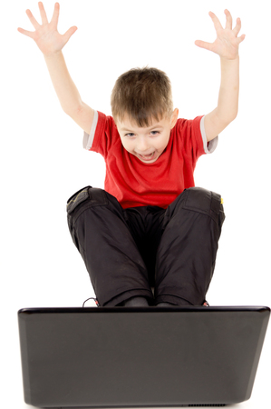 a small child happily looking into the notebook computer, raise up your hands isolated on white backgroundの写真素材