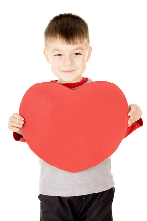 a small child stands and holds the heart isolated on white backgroundの写真素材