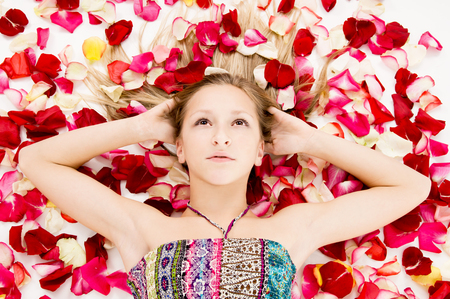 beautiful girl lies in the petals of roses, backgroundの写真素材