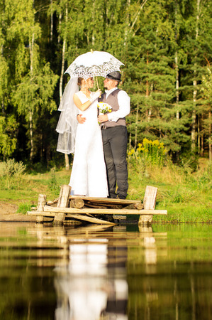 he bride and groom are standing on a wooden bridgeの写真素材