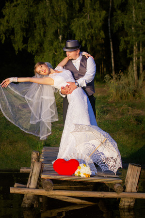 Happy bride and groom standing on a bridge in a forestの写真素材