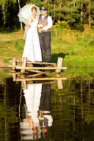 Bride and groom are standing on a bridge in a forestの写真素材