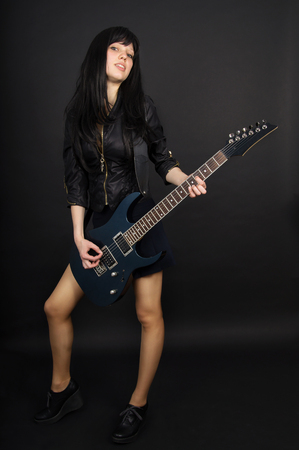 Girl playing guitar on black backgroundの写真素材