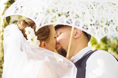 Beautiful bride and groom kissing under an umbrellaの写真素材